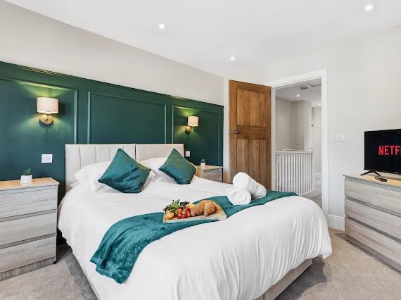 Bedroom styled with dark green feature wall and teal velvet bedding